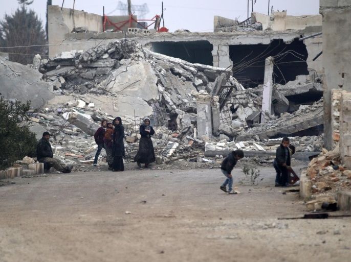 People stand near near rubble of damaged buildings in al-Rai town, northern Aleppo countryside, Syria December 25, 2016. REUTERS/Khalil Ashawi