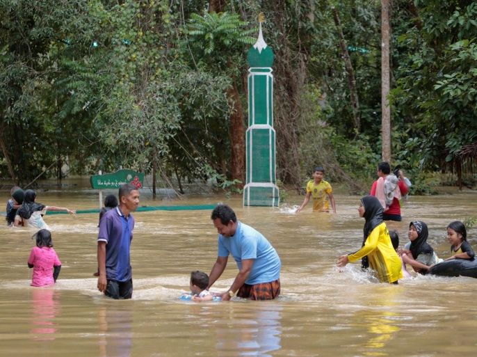 Thai Muslim villagers wade through a flooded street in Yala province, southern Thailand, January 21, 2017. REUTERS/Surapan Boonthanom