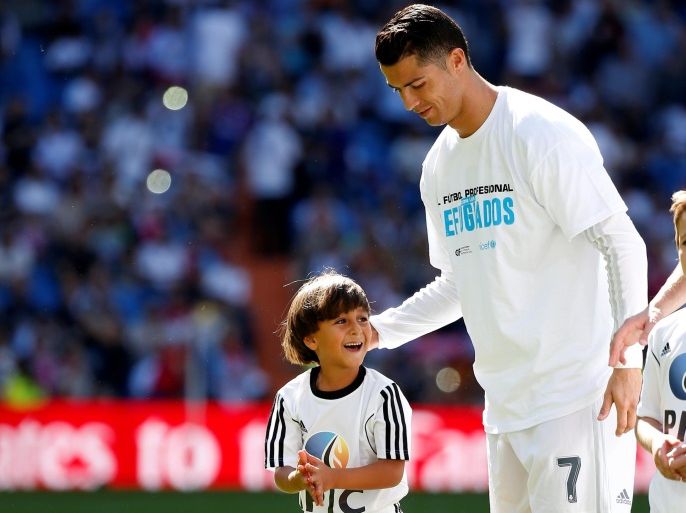 ATTENTION EDITORS: SPANISH LAW REQUIRES THAT THE FACES OF MINORS ARE MASKED IN PUBLICATIONS WITHIN SPAIN - Zaid, son of Osama Abdul Mohsen, smiles as he stands next to Real Madrid's Cristiano Ronaldo before the Spanish first division soccer match against Granada at Santiago Bernabeu stadium in Madrid, Spain, September 20, 2015. Mohsen's story went viral after he was filmed being tripped up by a camerawoman as he fled police near the Hungarian border with Serbia last S