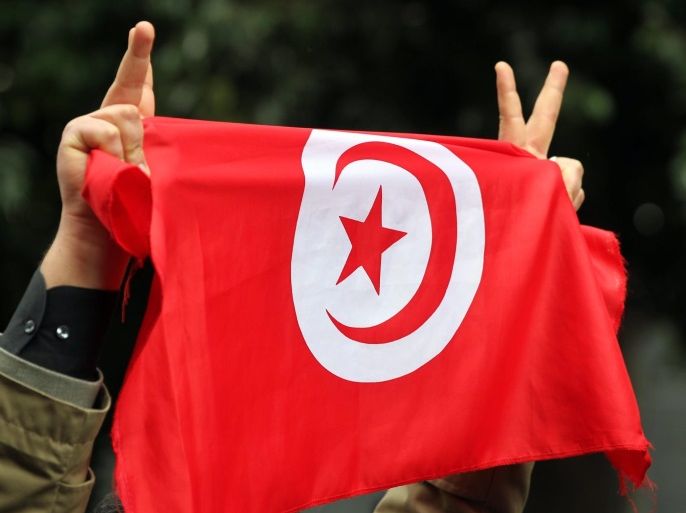 A Tunisian man holds the national flag and flashes the victory signs during a demonstration to put pressure on the authorities to ensure that those responsible for the assassination of Chokri Belaid be quickly identified, at the Avenue Habib Bourguiba in Tunis, Tunisia on 23 February 2013. Tunisian President Moncef Marzouki on 22 February approved Ali Larayedh to become Prime Minister and gave him two weeks to form a government. Larayedh, interior minister of the past 14 months, was nominated by the ruling Islamist party Ennahda to replace Hamadi Jebali who resigned following the assassination of opposition leader Chokri Belaid, the recent unrest and the impossibility to form a technocrat government.
