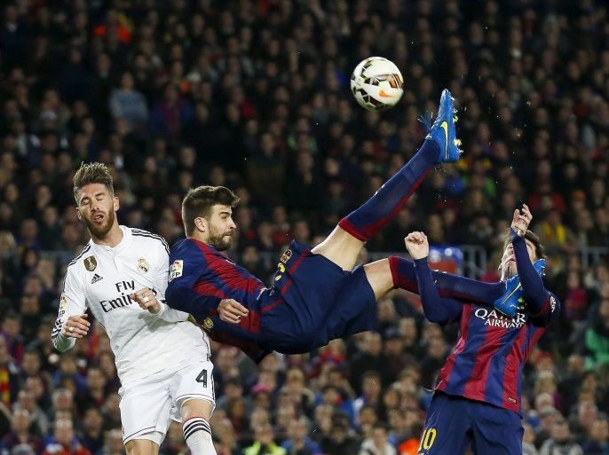 Barcelona's Gerard Pique (C) kicks the ball past Real Madrid's Sergio Ramos (L), as his team mate Lionel Messi looks on, during their Spanish first division