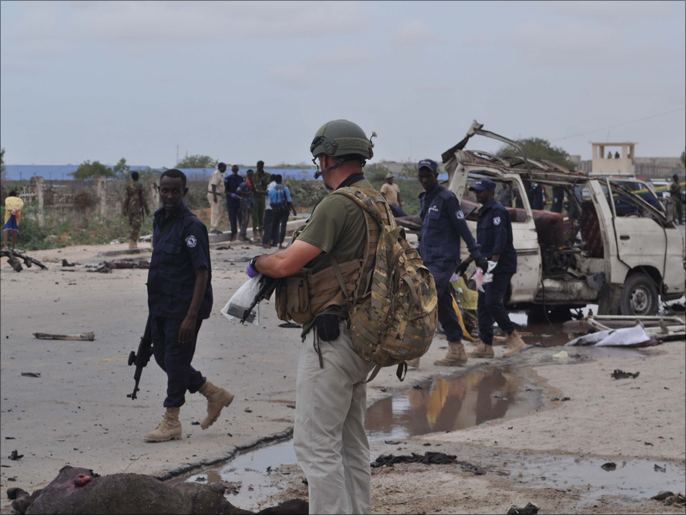 ‪‬ وحدة المتفجرات من الشرطة الصومالية ومدربوهم الأجانب يفحصون موقع التفجير(الجزيرة نت)