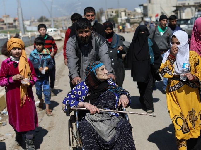 An Iraqi man pushes a wheelchair with an elderly woman as they walk along a street after fleeing their neighborhood in the city of Mosul, Iraq, April 4, 2017. REUTERS/Andres Martinez Casares