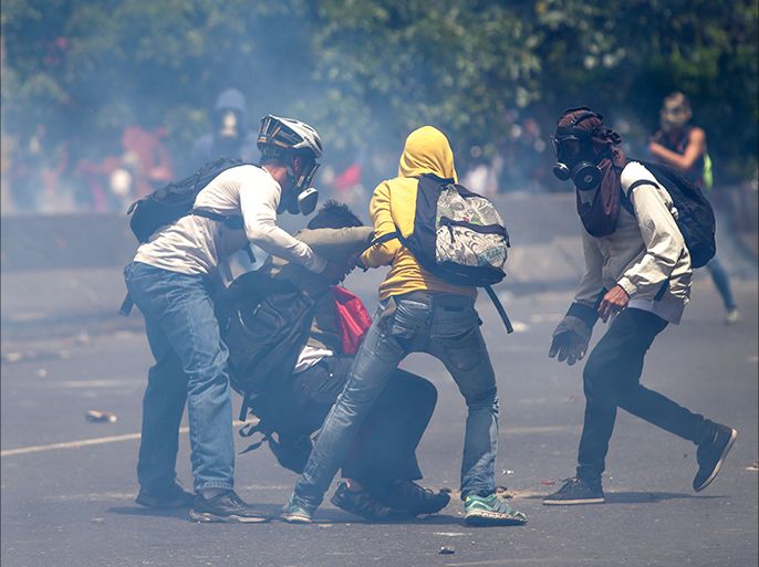 epa05916002 Demonstrators aid others during clashes with the police during an opposition protest in Caracas, Venezuela, on 19 April 2017. Venezuela is the scene of massive protests for both government supporters and opposition groups heightening tension throughout the country. EPA/CRISTIAN HERNANDEZ