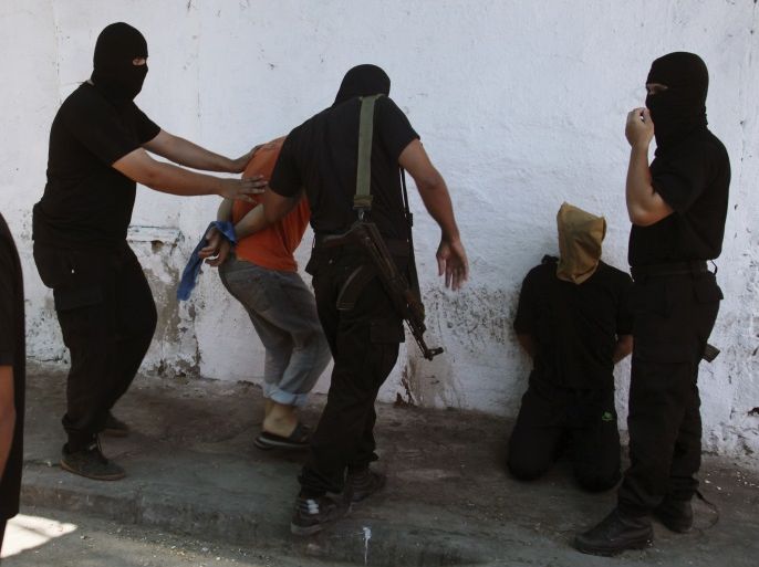 Hamas militants surround Palestinians suspected of collaborating with Israel before executing them in Gaza City August 22, 2014. Hamas militants killed seven Palestinians suspected of collaborating with Israel in a public execution in a central Gaza square on Friday, witnesses and a Hamas website said. The victims, their heads covered and hands tied, were shot dead by masked gunmen dressed in black in front of a crowd of worshippers outside a mosque after prayers, witnesses and al-Majd, a pro-Hamas website, said. Another 11 people suspected of collaborating with Israel were killed by gunmen at an abandoned police station in Gaza earlier on Friday, Hamas security officials said. REUTERS/Stringer (GAZA - Tags: POLITICS CIVIL UNREST MILITARY CONFLICT)