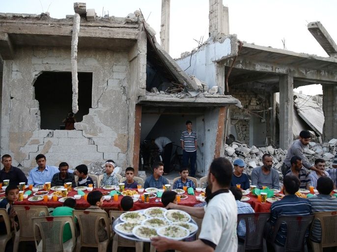 People gather amidst damaged buildings during Iftar (breaking fast), organised by Adaleh Foundation, during the holy month of Ramadan in the rebel held besieged Douma neighbourhood of Damascus, Syria June 18, 2017. Picture taken June 18, 2017. REUTERS/Bassam Khabieh