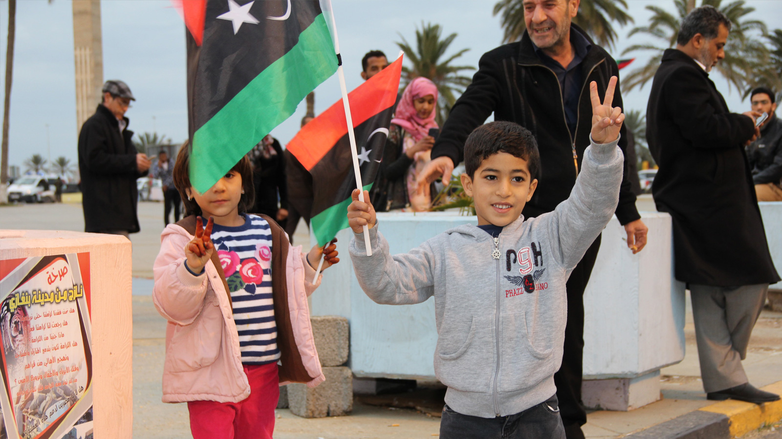 ‪‬ طفل يرفع علم ليبيا في ميدان الشهداء أثناء احتفالات بذكرى الثورة(الجزيرة-أرشيف)