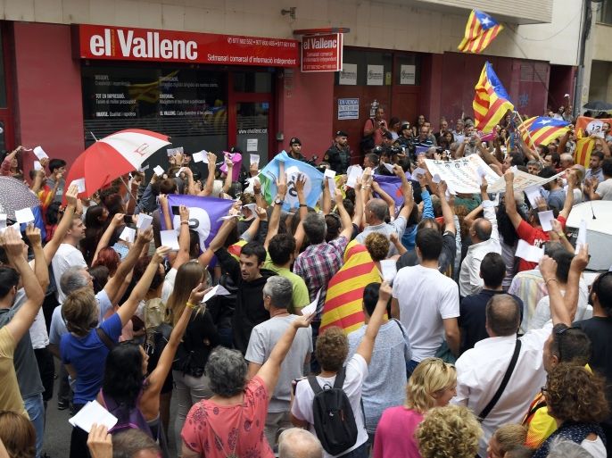 People hold up ballots for the Catalan referendum on independence as they protest against a police search in the headquarters of the weekly newspaper 'El Vallenc' in Valls, on September 9, 2017.The Spanish Civil Guard searched today 'El Vallenc' newspaper's headquarters in Valls, which would be suspected of having printed ballots for the banned referendum on independence in Catalonia, convened for October 1. / AFP PHOTO / Lluis GENE (Photo credit should read LLUIS GENE/AFP/Getty Images)