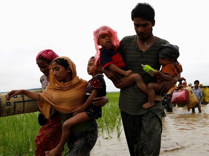 A group of Rohingya refugees carry their children as the wade across water after travelling over the Bangladesh-Myanmar border in Teknaf, Bangladesh, September 1, 2017. REUTERS/Mohammad Ponir Hossain