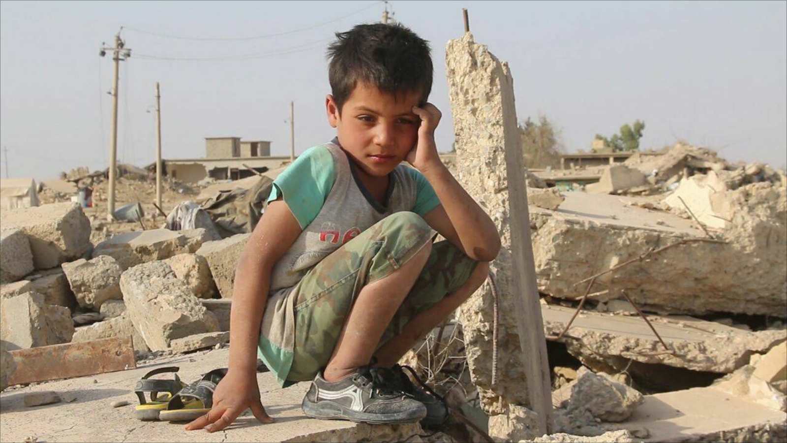 ‪طفل يجلس على أنقاض منزله المهدم بناحية زمار شمال غربي الموصل‬ (الجزيرة)