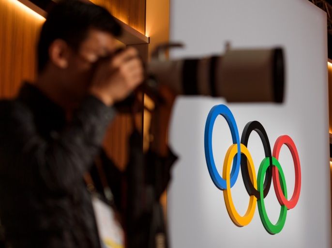 A press photographer takes a picture next to the Olympic Rings logo during the 131st IOC session in Lima on September 15, 2017. / AFP PHOTO / Fabrice COFFRINI (Photo credit should read FABRICE COFFRINI/AFP/Getty Images)