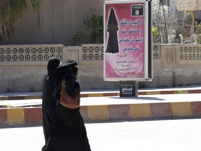Veiled women walk past a billboard that carries a verse from Koran urging women to wear a hijab in the northern province of Raqqa March 31, 2014. The Islamic State in Iraq and the Levant (ISIL) has imposed sweeping restrictions on personal freedoms in the northern province of Raqqa. Among the restrictions, Women must wear the niqab, or full face veil, in public or face unspecified punishments