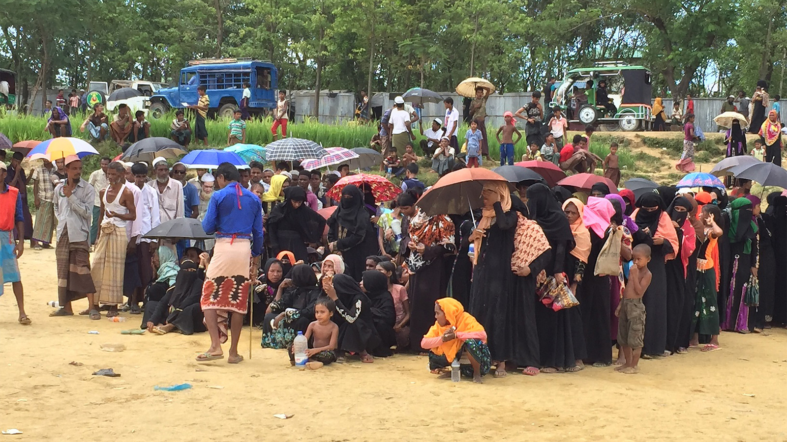 نساء ورجال من أقلية الروهينغا عند الحدود بين بنغلاديش وميانمار في انتظار توزيع بعض الوجبات الغذائية  (الجزيرة)