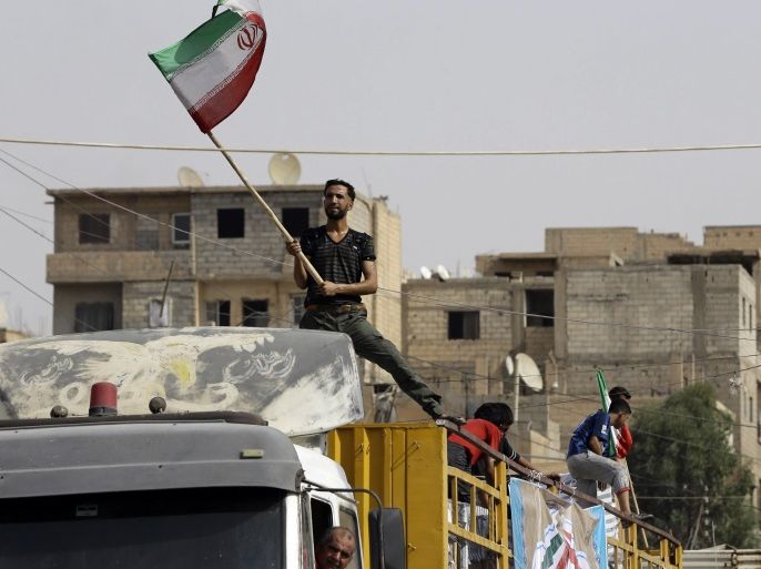 A Syrian man holds the Iranian flag as a convoy carrying aid provided by Iran arrives in the eastern city of Deir Ezzor on September 20, 2017 while Syrian government forces continue to press forward with Russian air cover in the offensive against Islamic State group jihadists across the province.Two separate offensives are under way against the jihadists in the area -- one by the US-backed Syrian Democratic Forces, the other by Russian-backed government forces. The Syri