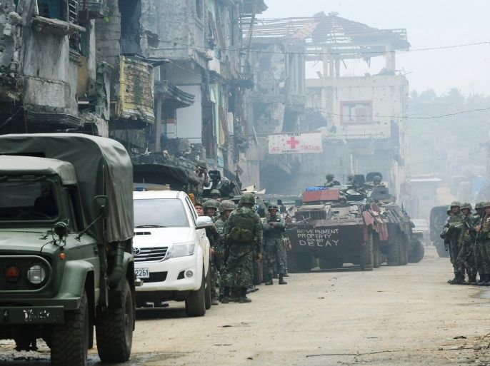 An Armoured Personnel Carrier (APC) and government troops stand on guard in front of damaged buildings and houses after 100 days of intense fighting between soldiers against insurgents from the Maute group, who have taken over parts of Marawi city, southern Philippines August 30, 2017. REUTERS/Froilan Gallardo