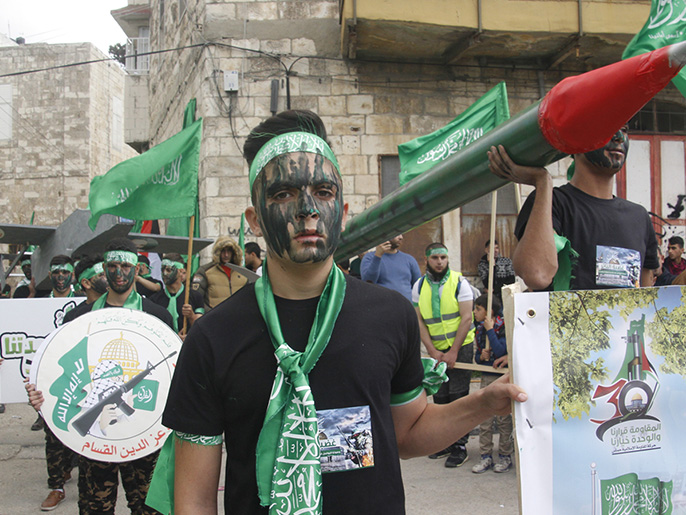 شبان من حماس يحملون مجسما لصاروخ بالاحتفال في نابلس بالذكرى الثلاثين لانطلاقتها