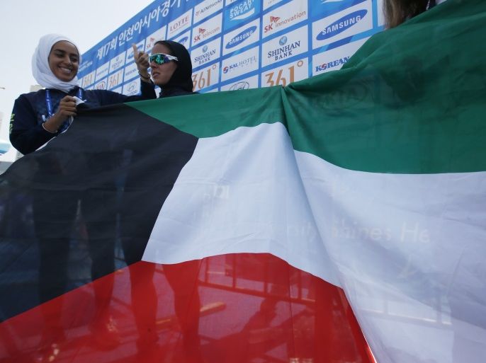 Kuwait's Najlaa I M Aljerewi (R), wearing a hijab, holds her national flag with her sister after finishing the course during the women's triathlon competition at Songdo Central Park during the 17th Asian Games in Incheon September 25, 2014. REUTERS/Kim Kyung-Hoon (SOUTH KOREA - Tags: SPORT TRIATHLON)
