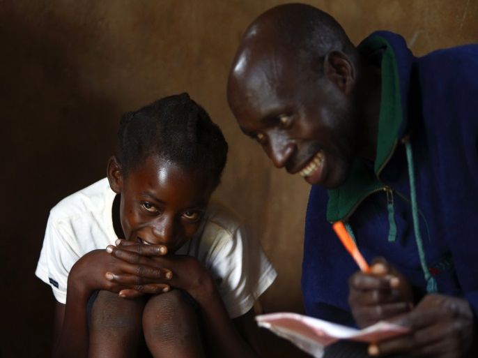11-year-old Sonia Matanga (L), who was born HIV-positive, attends a self-help group meeting with caregiver Davison Mungoni (R) in the village of Michelo, south of the Chikuni Mission in the south of Zambia February 23, 2015. The caregivers in the Jesuit-run home-based care project at the Chikuni Mission run a capacity-building and empowerment project at the household level, offering training and assistance in crop-growing and animal rearing, as well as offering companionship, pastoral care and monitoring antiretroviral treatment compliance of HIV-AIDS patients. REUTERS/Darrin Zammit Lupi (ZAMBIA - Tags: SOCIETY HEALTH)