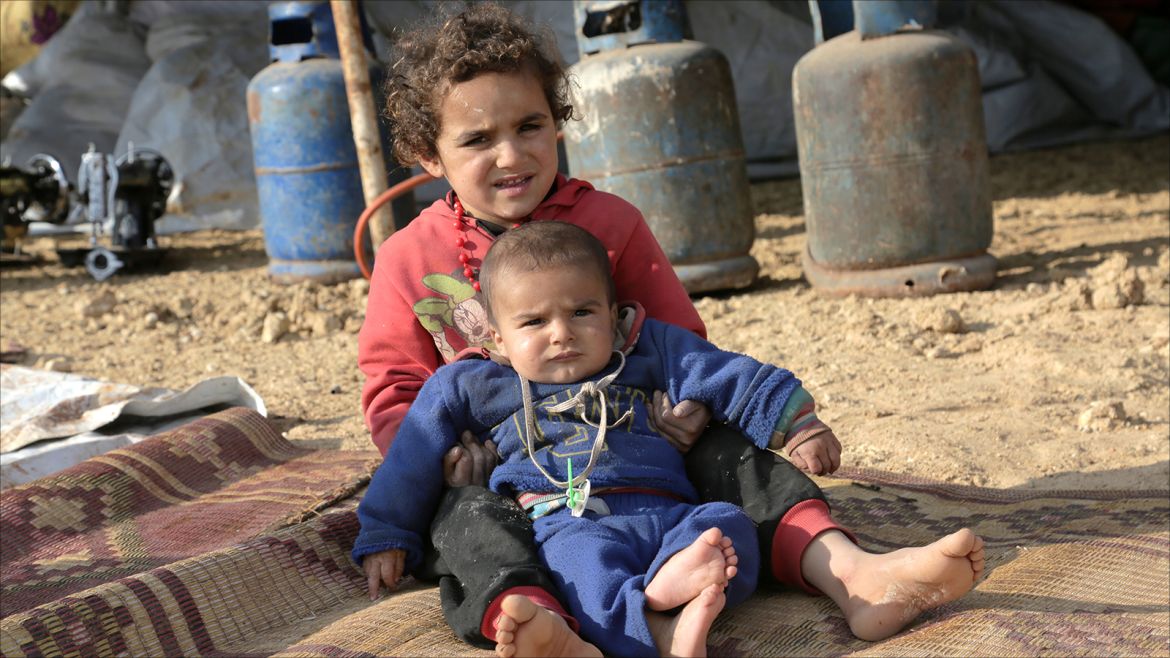 epa06421135 Internally displaced children sit at the Kalbeed makeshift camp, near Bab al-Hawa crossing by the Syrian-Turkish border, 06 January 2018. Hundreds of families fled the fighting between government and opposition forces around Idlib.  EPA-EFE/ZEIN ALRIFAII