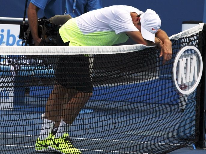 Adrian Mannarino of France leans on the net after retiring from his match from the heat stress during his men's singles second round match against Feliciano Lopez of Spain at the Australian Open 2015 tennis tournament in Melbourne January 22, 2015. REUTERS/John French (AUSTRALIA - Tags: SPORT TENNIS)