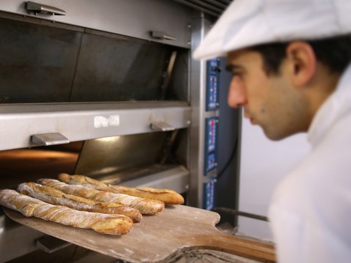 Baker Sylvain Cabane takes out of the oven a tray of baguettes at the bakery