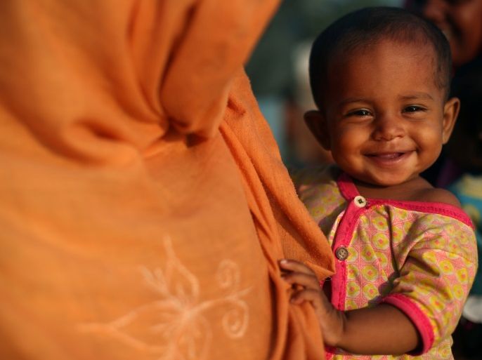 Ayesha, a 10-month-old Rohingya refugee girl smiles as she is carried by her mother Fatema, 20 as they wait at a port to receive permission from the Bangladeshi army to continue their way after crossing from Myanmar, in Teknaf, Bangladesh, October 25, 2017. REUTERS/Hannah McKay
