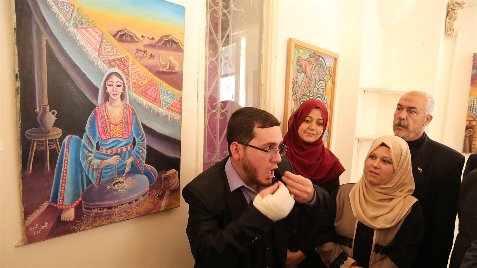 المقيد يشرح لوحة لسيدة فلسطينية تلبس زيا تراثيا فلسطينيا (الجزيرة)