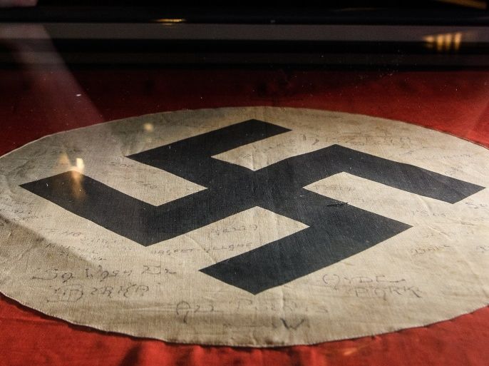 LONDON, ENGLAND - MARCH 15: A gallery assistant poses with a captured Nazi swastika flag, signed by original members of the SAS, listing their missions in Africa during World War II, at the National Army Museum on March 15, 2018 in London, England. 'Special Forces: In the Shadows' is a new exhibition, exploring the background and equipment used by the British Army Special Forces, and runs from 17 March to 18 November 2018. (Photo by Leon Neal/Getty Images)