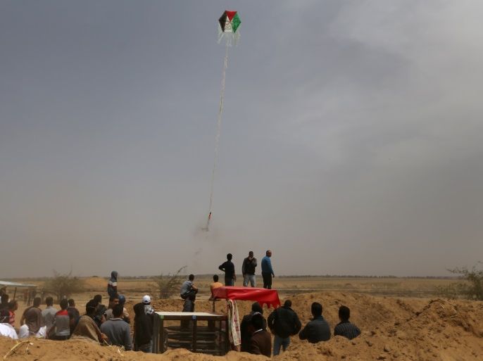 Palestinians set a kite on fire to be thrown at the Israeli side during clashes at a protest demanding the right to return to their homeland, at the Israel-Gaza border in the southern Gaza Strip, April 20, 2018. REUTERS/Ibraheem Abu Mustafa