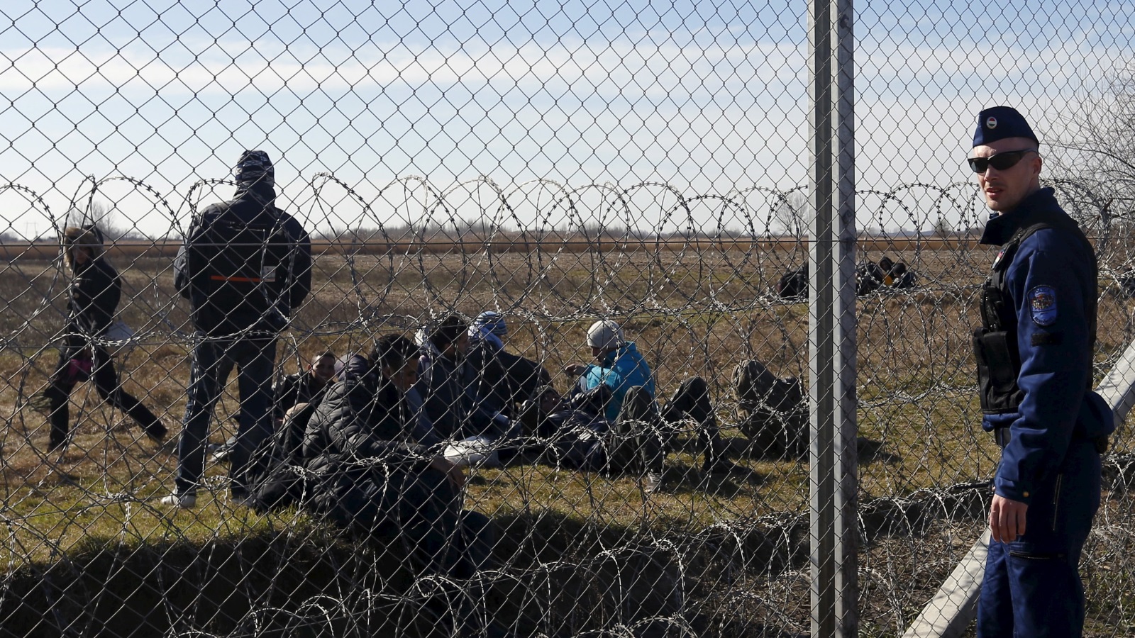 مجموعة من اللاجئين أمام السياج الحدودي بين المجر وصربيا (غيتي)