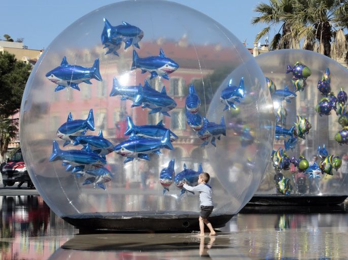 A boy looks at fish-shaped balloons installed in a water fountain to mark April Fools' Day, called