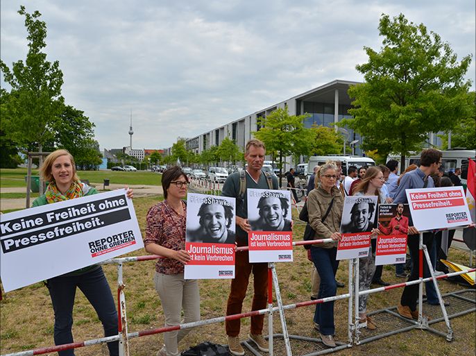 ممثلون لمنظمة مراسلون يرفعون صور شوكان احتجاجا على اعتقاله خلال زيارة السيسي لبرلين . الجزيرة نت .