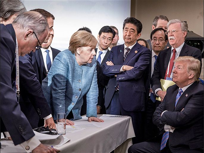 epa06797185 A handout photo made available by the German Government (Bundesregierung) on 09 June 2018 shows French President Emmanuel Macron (3-L, partially hidden), German Chancellor Angela Merkel (C-L) and Japan's Prime Minister Shinzo Abe (C-R) speaking to US Presidend Donald J. Trump (R, seated) during the second day of the G7 meeting in Charlevoix, Canada, 09 June 2018. Looking on is US National Security Advisor John R. Bolton (R, standing); others are not identified. EPA-EFE/JESCO DENZE HANDOUT HANDOUT EDITORIAL USE ONLY/NO SALES