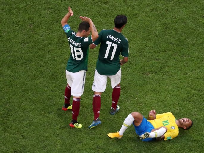 SAMARA, RUSSIA - JULY 02: Neymar Jr of Brazil lies on the pitch injured while Andres Guardado and Carlos Vela of Mexico pass by during the 2018 FIFA World Cup Russia Round of 16 match between Brazil and Mexico at Samara Arena on July 2, 2018 in Samara, Russia. (Photo by Clive Rose/Getty Images)