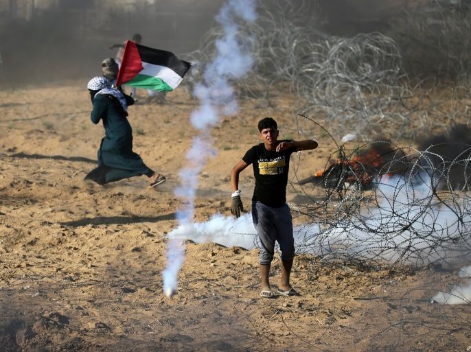 Palestinians react to tear gas fired by Israeli troops during a protest at the Israel-Gaza border in the southern Gaza Strip July 13, 2018. REUTERS/Ibraheem Abu Mustafa