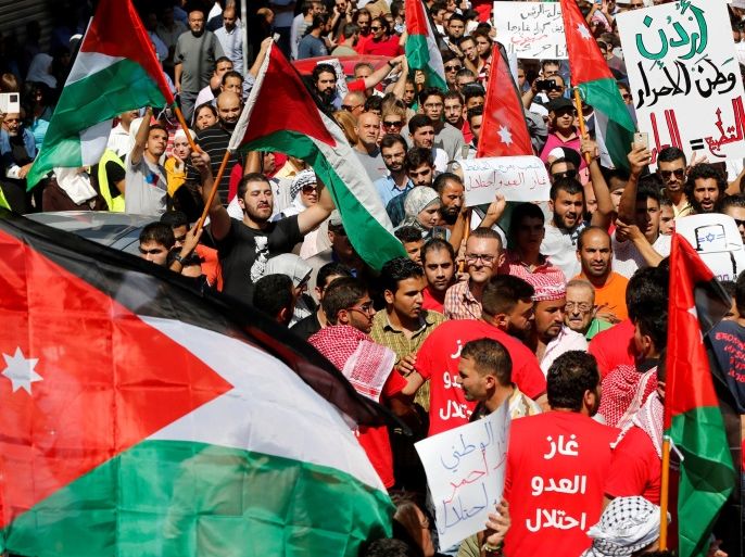 Jordanian protesters carry the Jordanian national flags, and chant slogans during a protest against a government agreement to import natural gas from Israel, in Amman, Jordan, September 30, 2016. The right placard reads,
