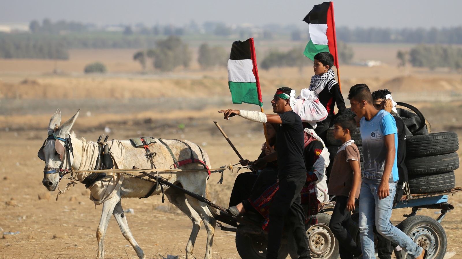 ‪فلسطينيون ينقلون إطارات لحرقها على السياج الحدودي في غزة‬  فلسطينيون ينقلون إطارات لحرقها على السياج الحدودي في غزة (رويترز)
