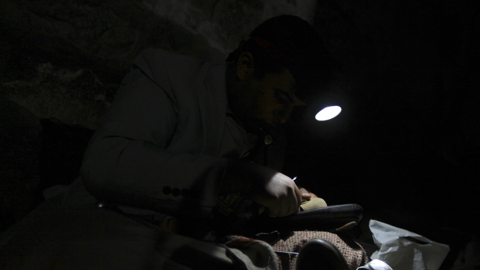 ‪يمني يصلح حذاء على ضوء خافت‬  يمني يصلح حذاء على ضوء خافت (رويترز)