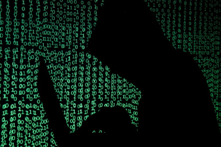A hooded man holds a laptop computer as cyber code is projected on him in this illustration picture taken on May 13, 2017. Capitalizing on spying tools believed to have been developed by the U.S. National Security Agency, hackers staged a cyber assault with a self-spreading malware that has infected tens of thousands of computers in nearly 100 countries. REUTERS/Kacper Pempel/Illustration