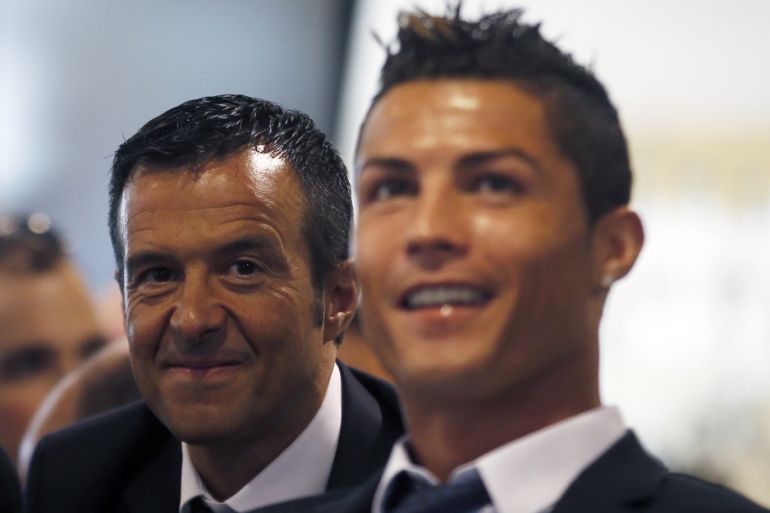Real Madrid's Cristiano Ronaldo (R) reacts while watching a video as he sits next to his agent Jorge Mendes during a ceremony at Santiago Bernabeu stadium in Madrid September 15, 2013. Ronaldo has agreed a contract extension with Real Madrid, the La Liga club said on Sunday. REUTERS/Sergio Perez (SPAIN - Tags: SPORT SOCCER)
