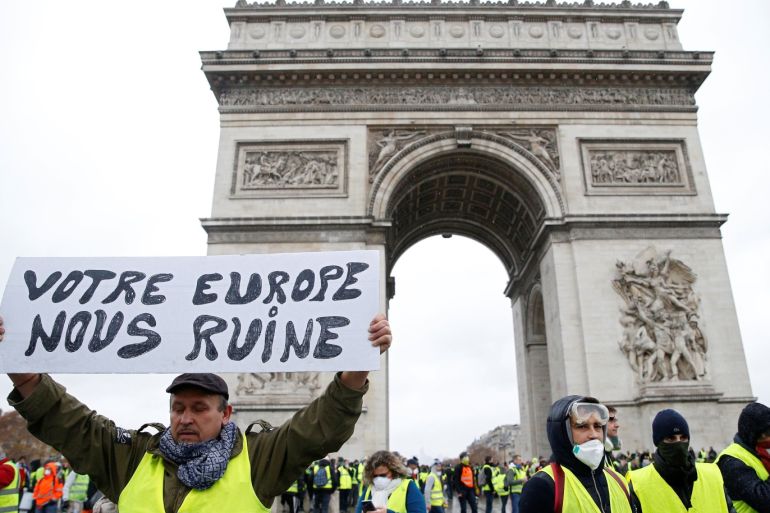 Protesters wearing yellow vests, a symbol of a French drivers' protest against higher diesel taxes, demonstrate in Paris, France, December 1, 2018. Placard reads,