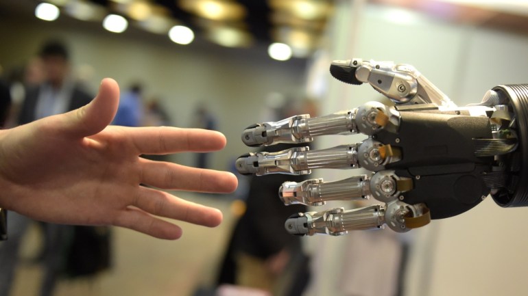 A man moves his hand toward SVH (Servo Electric 5 Finger Gripping Hand) automated hand made by Schunk during the 2014 IEEE-RAS International Conference on Humanoid Robots in Madrid on November 19, 2014. The conference theme 'Humans and Robots Face-to-Face' confirms the growing interest in the field of human-humanoid interaction and cooperation, especially during daily life activities in real environments. AFP PHOTO/ GERARD JULIEN (Photo credit should read GERAR