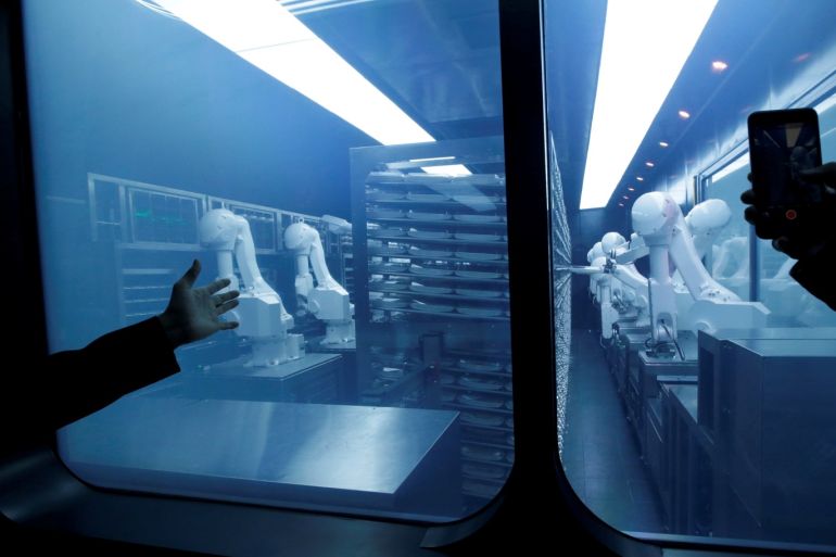 A customer takes a picture as robotic arms collect pre-packaged dishes from a cold storage, done according to the diners' orders, at Haidilao's new artificial intelligence hotpot restaurant in Beijing, China, November 14, 2018. Picture taken November 14, 2018. REUTERS/Jason Lee TPX IMAGES OF THE DAY
