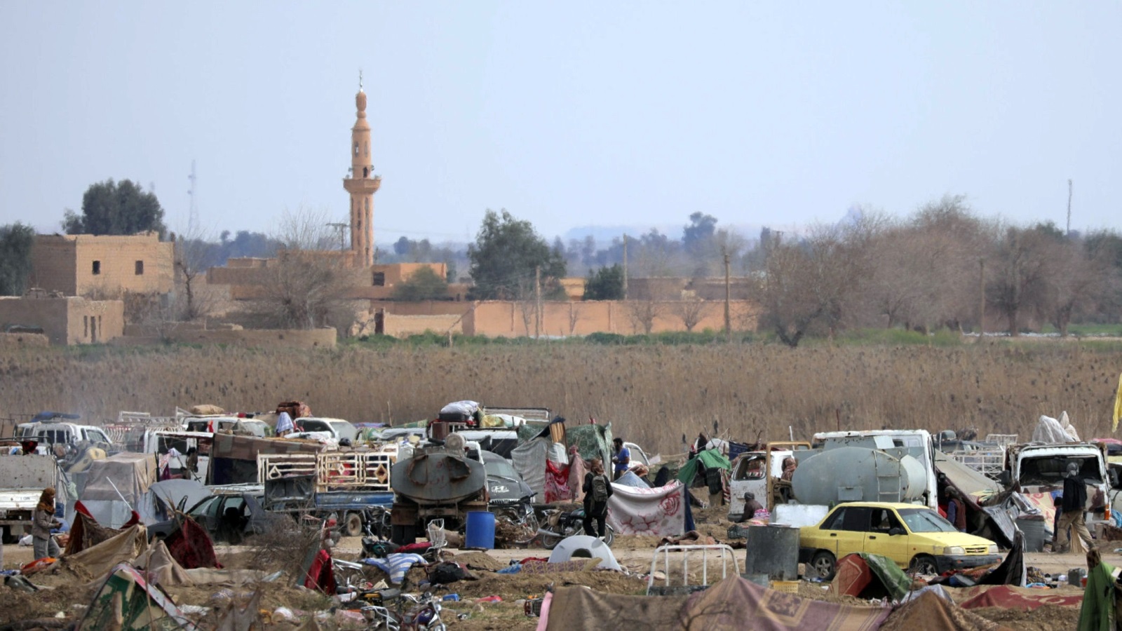 عناصر من تنظيم الدولة يتجولون بمخيم لهم في أطراف الباغوز (رويترز)