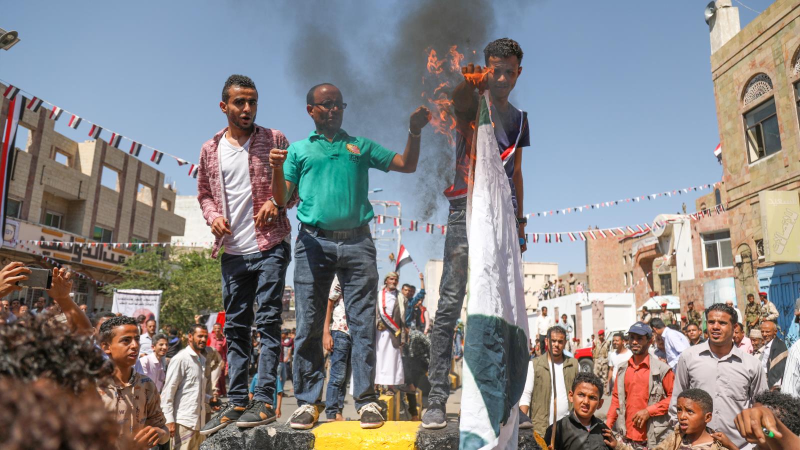 يمنيون يحرقون أعلام السعودية والإمارات احتجاجا على عدم مساعدتهم في وقف الانهيار الاقتصادي (الجزيرة)