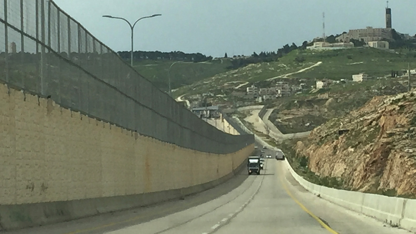 ‪الشارع الذي يحاصر عناتا من الجهة الشرقية ويظهر الجدار الفاصل عن شارع للمستوطنين بجانبه‬  (الجزيرة)
