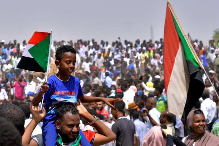 Sudanese demonstrators chant slogans and carry their national flags after Sudan's Defense Minister Awad Mohamed Ahmed Ibn Auf said that President Omar al-Bashir had been detained