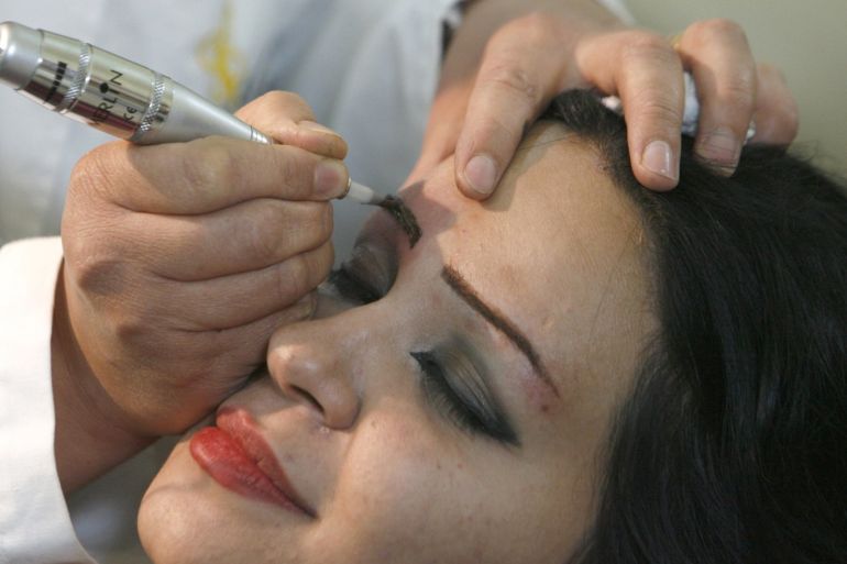 Iraqi beautician Ina'am Hikmet tattoos a client's eyebrows in Baghdad May 3, 2009. Picture taken May 3, 2009. REUTERS/Thaier al-Sudani (IRAQ SOCIETY)
