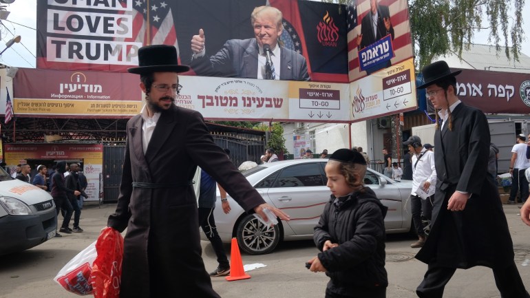 UMAN, UKRAINE - SEPTEMBER 09: Hassidic Jews walk past a banner that reads: 'Uman Loves Trump', in reference to U.S. President Donald Trump, who is popular among Orthodox Jews, prior to the annual Rosh Hashanah celebration on September 9, 2018 in Uman, Ukraine. Tens of thousands of Hasidic and Orthodox Jews, including many Breslov (also called Bratslav) Hasidim, a specific group of Hasidic Jews, have made the annual journey from all over the world to Uman to visit the tomb of Rebbe Nachman of Breslov, who founded the Breslov sect in 1802. The pilgrims come for a spiritual experience and religious discussions, but also to celebrate in what one participant describes as a 'Jewish Woodstock.' The Breslov sect grew, attracting thousands of followers, until Stalin's purges and decimation in the Holocaust. Breslov Hasidism has since revived and its followers live mostly in Israel, the United States and Great Britain. (Photo by Sean Gallup/Getty Images)