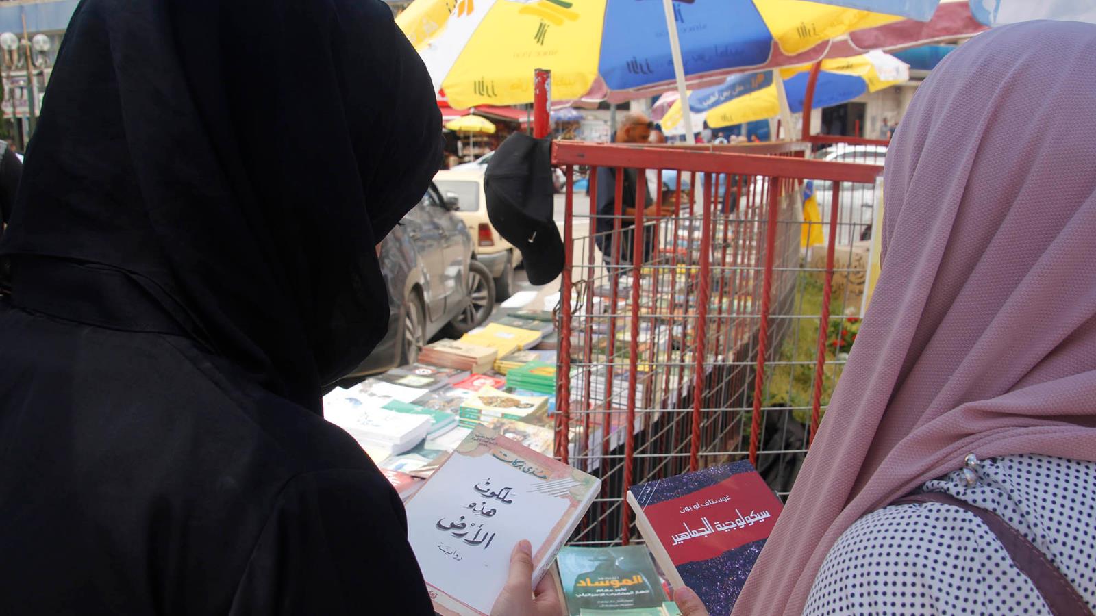 ‪فتاتان تطالعان كتبا في المعرض الذي أقيم في ميدان الشهداء‬ (الجزيرة)